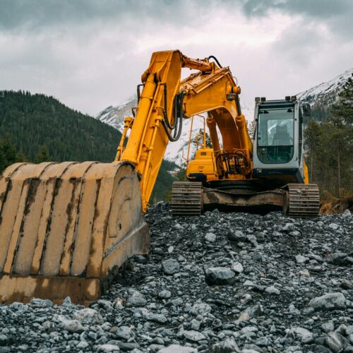 yellow and black excavator on rocky ground